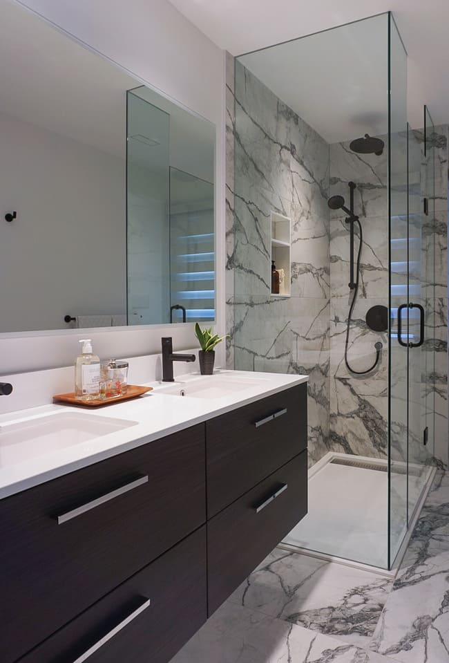 Niagara bathroom renovation with black vanity, white counters, and glass shower