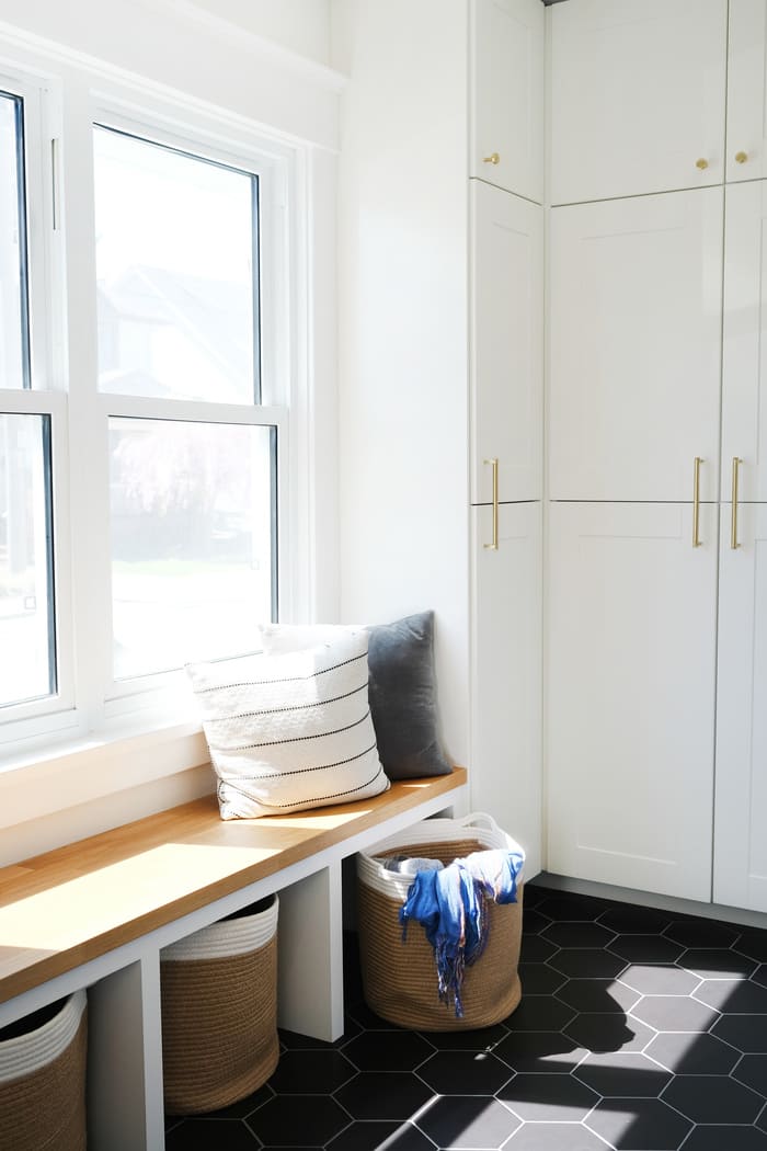Niagara mudroom renovation with wooden bench, white cabinetry and black tile
