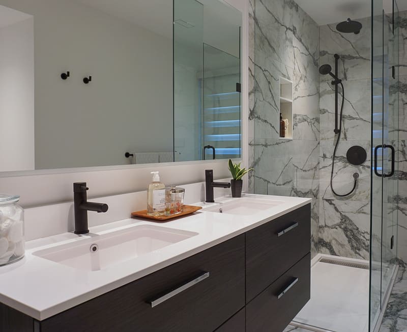 Niagara bathroom renovation with black vanity and white counters and glass shower